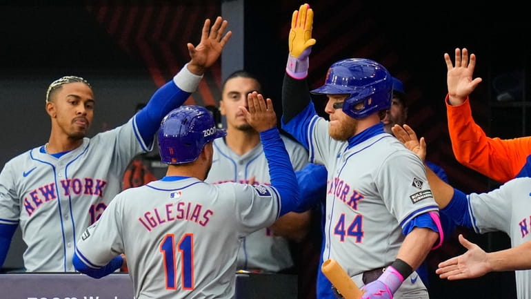 The Mets' Jose Iglesias is greeted in the dugout after scoring...