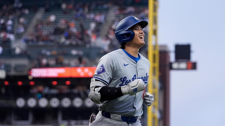 Los Angeles Dodgers' Shohei Ohtani smiles as he jogs to...