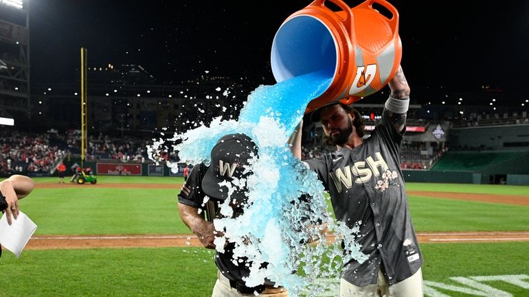 Washington Nationals' Jacob Young, left, is doused by Jesse Winker,...