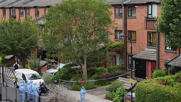 Forensic officers stand, at an address in Shepherd's Bush, after...