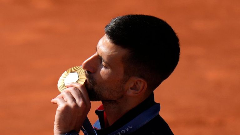 Serbia's Novak Djokovic kisses his gold medal after defeating Spain's...