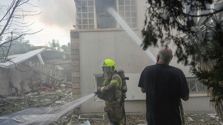 Israeli firefighters extinguish fire after a rocket fired from the...