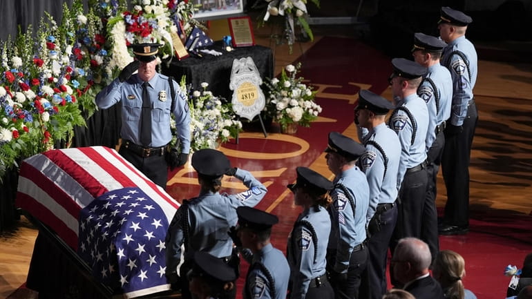 Law enforcement officers salute during a public memorial service for...