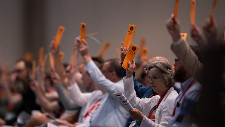 Messengers raise their ballots in support of a resolution put...