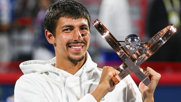 Alexei Popyrin, of Australia, holds up the winner's trophy after...