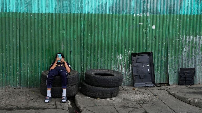 A teenager sits on a short stack of tires as...