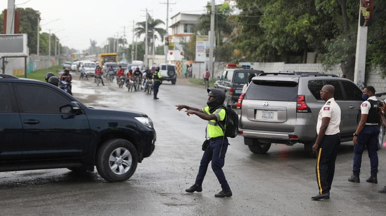A police officer directs a caravan transporting Haiti's new Prime...