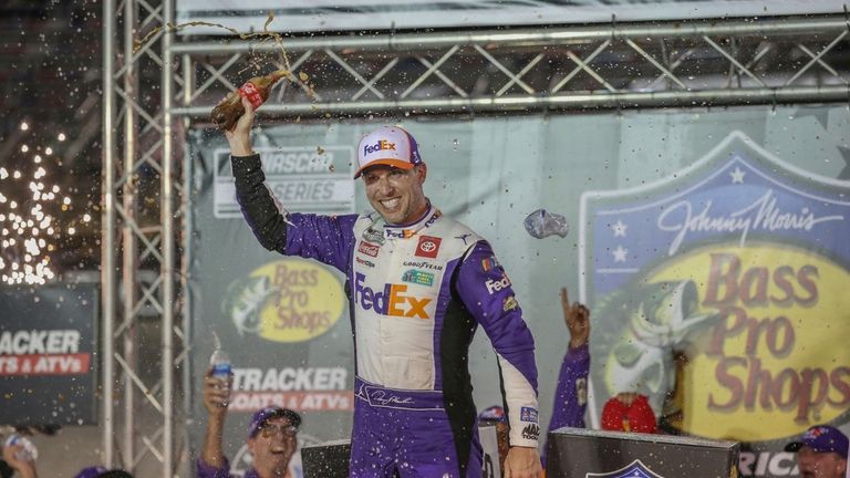 Denny Hamlin celebrates in Victory Lane with the team after...