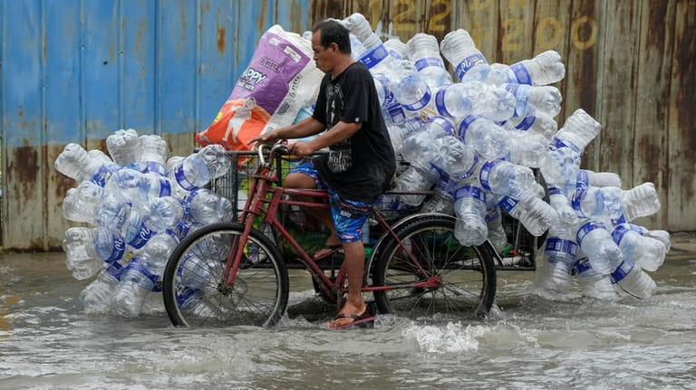 A man uses his pedicab to transport used plastic containers...