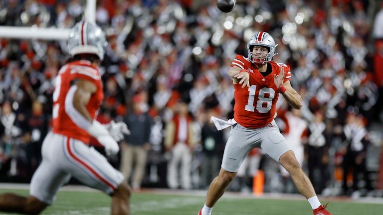 Ohio State quarterback Will Howard, right, throws a pass to...