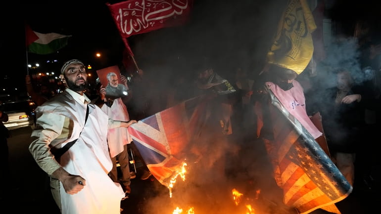 Iranian demonstrators burn representations of British and U.S. flags during...