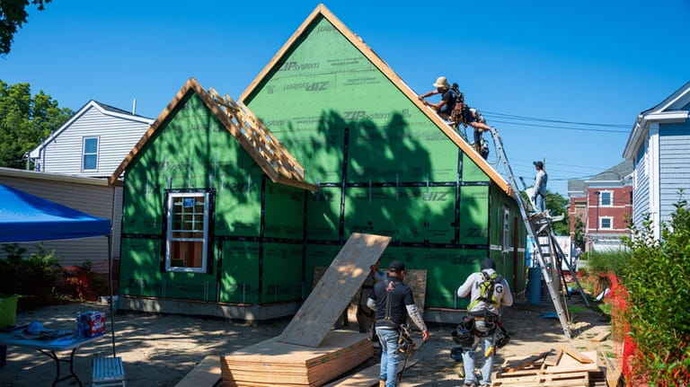 Workers installed roofing Tuesday at a Habitat for Humanity of...