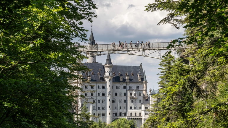 People stay on the Marien-Bridge at Castle Neuschwanstein, a 19th...