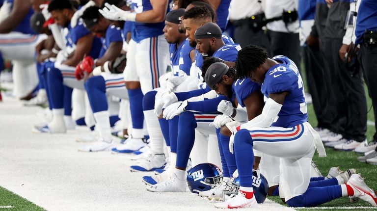 The Giants stand and kneel during the national anthem prior to...