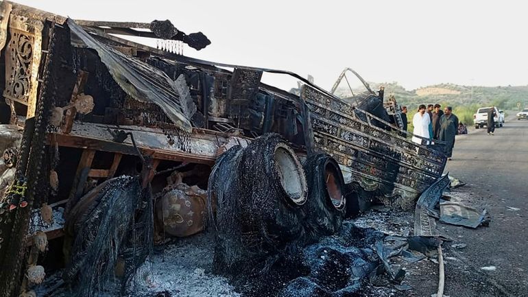 People look at a burnt vehicle which was torched by...