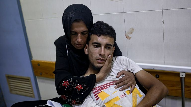 A Palestinian woman hugs her son wounded in the Israeli...