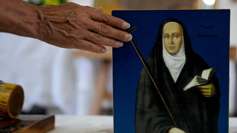 A devotee touches a painting depicting María Antonia de Paz...