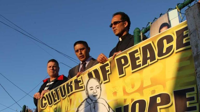 Reverend Allan B. Ramirez, right, and Joselo Lucero, center, stand...