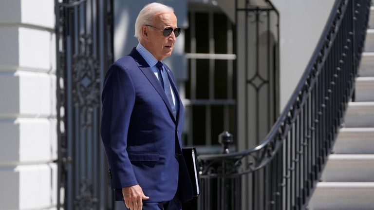 President Joe Biden walks out of the White House to...