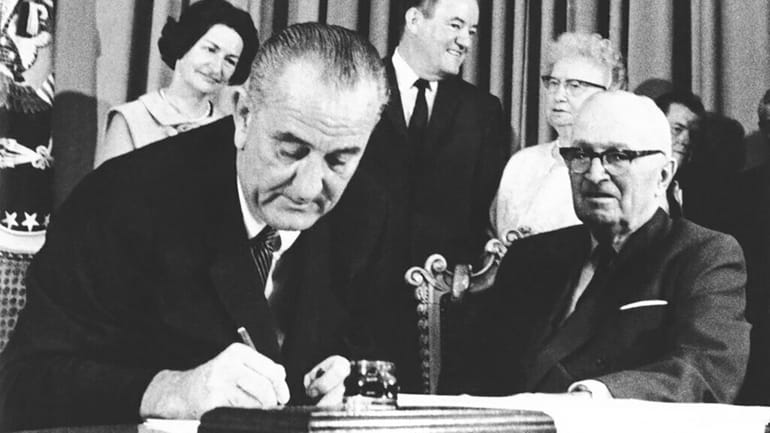 President Lyndon B. Johnson signs the Medicare bill in Independence,...