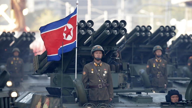 North Korean soldiers stand on armored vehicles with rocket launchers...