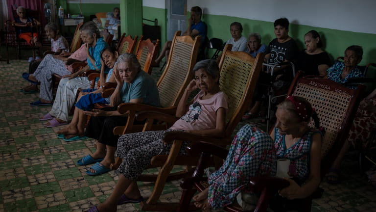 Isabel Rios, 73, center, sits with others by the window...