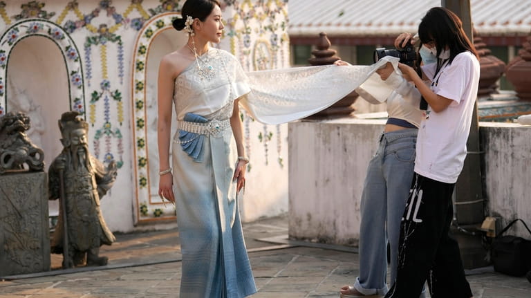 A Chinese tourist rents traditional Thai costumes and poses for...