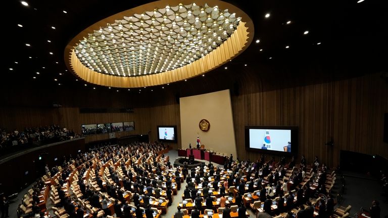 South Korean lawmakers salute to a national flag during the...