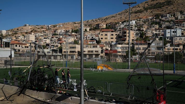 People visit the site of a rocket strike that killed...