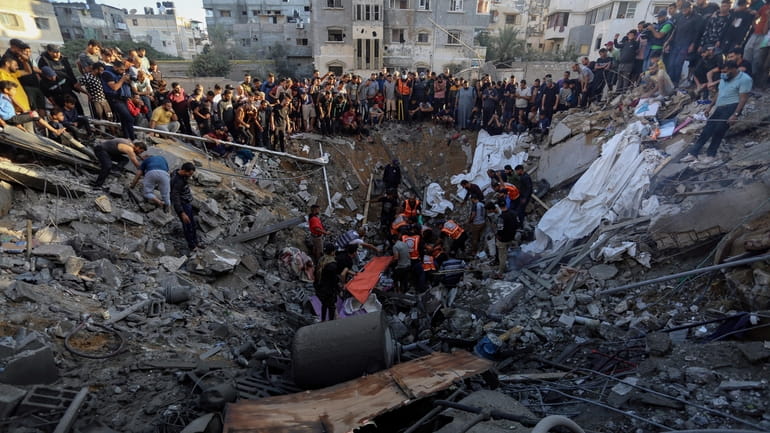 Palestinians gather over the remains of a destroyed house following...