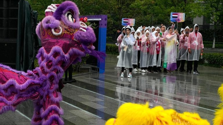 Athletes from Yemen take photos of a dragon dance performance...