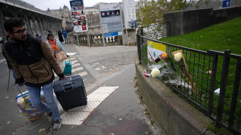 A man walks past flowers placed on the scene where...