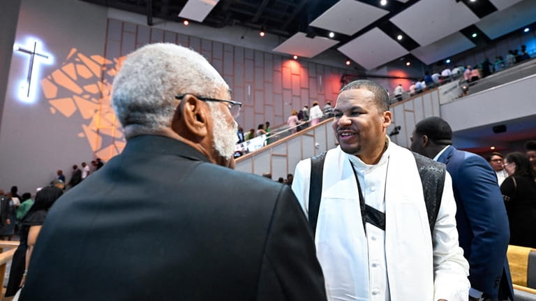 Reverend Matthew L. Watley, right, greets members of the congregation...