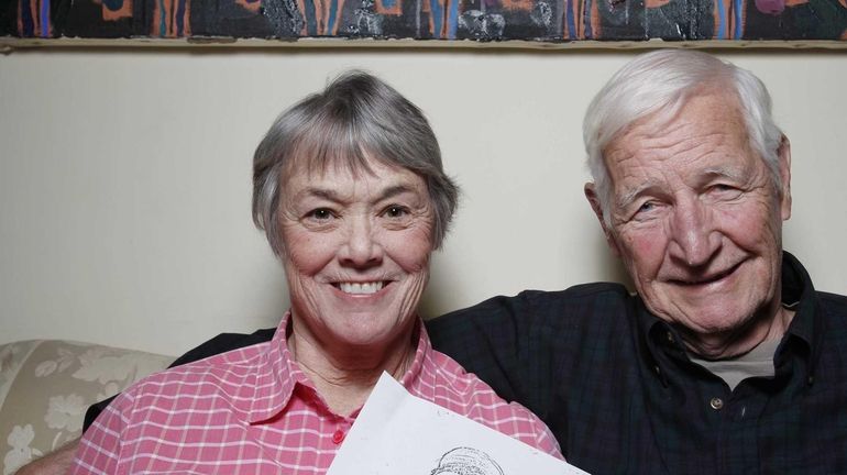 Bonnie Raines sits with her husband, John, and holds a...