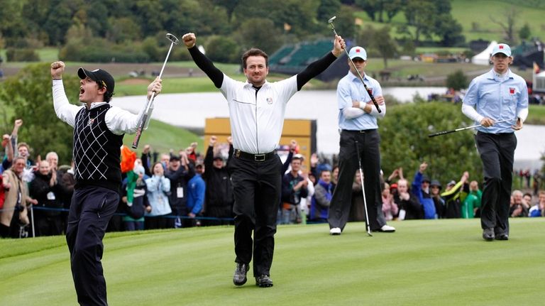 Europe's Rory McIlroy, left, and Graeme McDowell, second left, react...