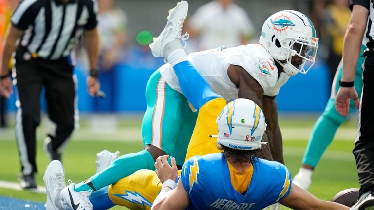 Los Angeles Chargers quarterback Justin Herbert, bottom, is sacked by...