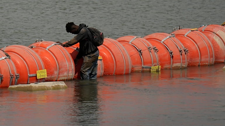 A migrant from Columbia stands at a floating buoy barrier...