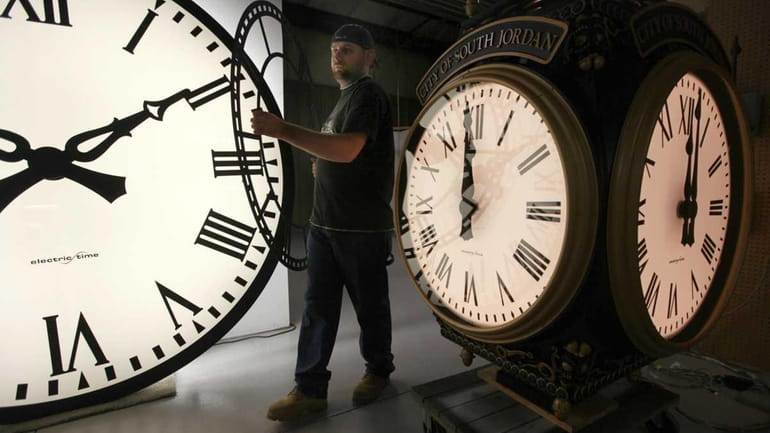 Dan LaMoore of Electric Time Co. moves a clock face...