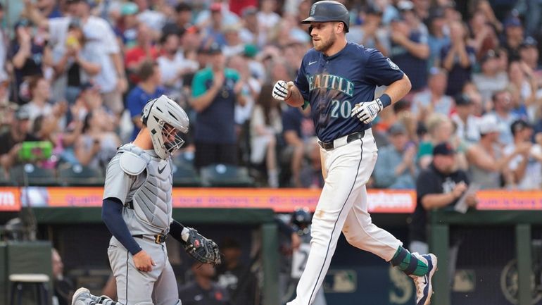 Seattle Mariners' Luke Raley (20) crosses home after hitting a...