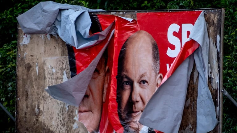 A damaged election poster shows German Chancellor Olaf Scholz in...