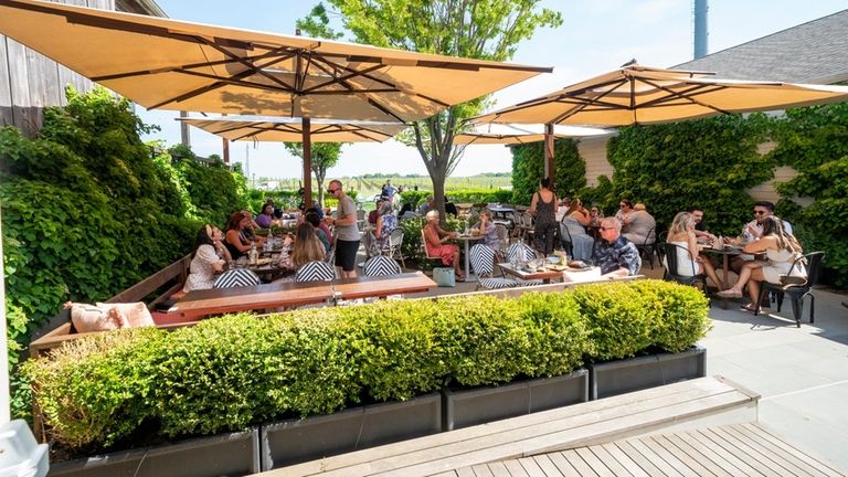 Guests taste wine on one of outdoor patios at Rose...