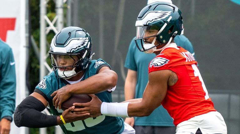 Eagles running back Saquon Barkley, left, takes the hand off...