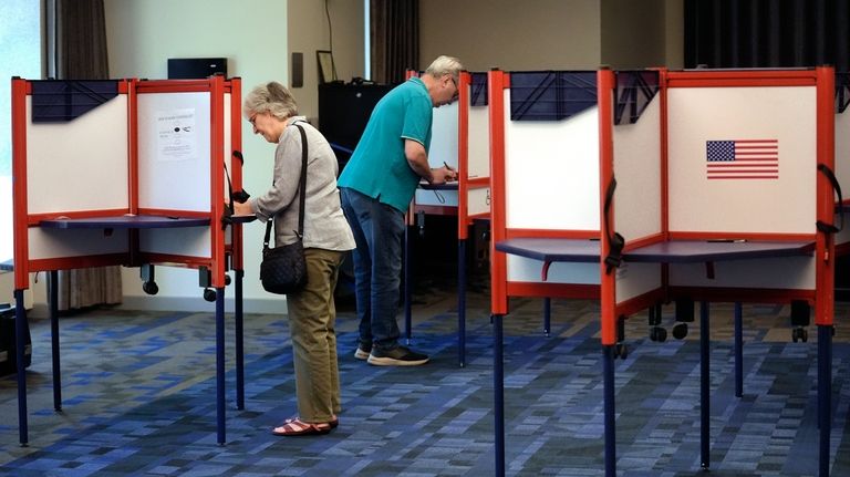 Voters fill out their ballots at a polling station during...