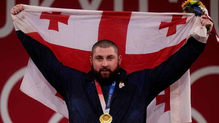 Lasha Talakhadze of Georgia holds his national flag as he...