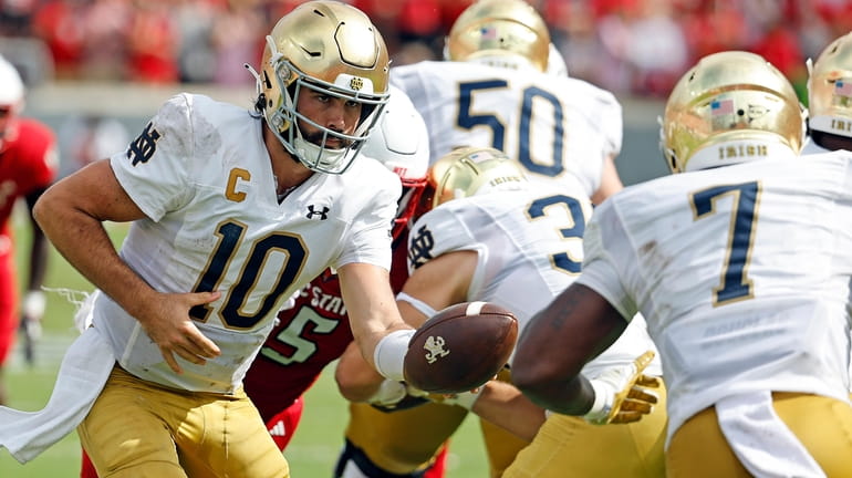 Notre Dame's Sam Hartman (10) hands the ball off to...