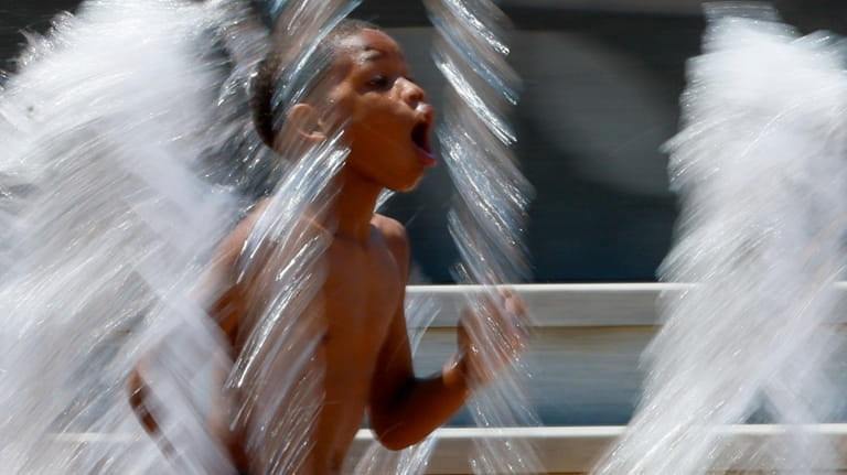 A kid runs splashing water at the Centennial Olympic Park...