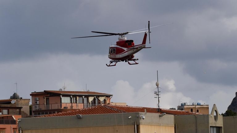 An Italian Firefighters helicopter flies over houses near the harbor...