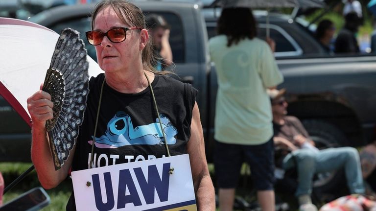 Assembly line worker Sheila Buckley tries to keep cool while...