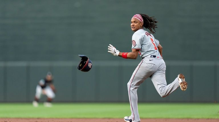 Washington Nationals' CJ Abrams (5) looks back while stealing second...