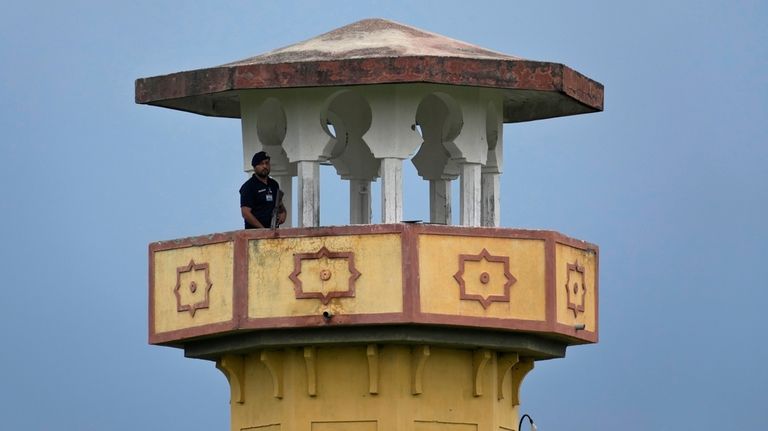 A police officer stands guard on a watch tower of...